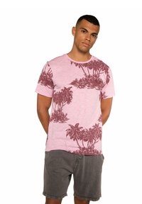 T-shirt rosa chiaro realizzata in morbido tessuto, con motivi di palme color bordeaux. Design con collo a giro e maniche corte.