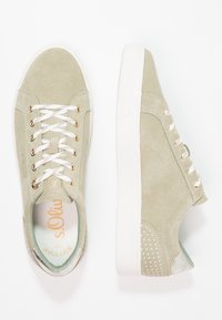 Světle zelené semišové tenisky se zlatými očky a bílými tkaničkami, s texturovaným kovovým detailem a tečkovaným designem na patě.