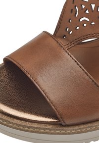 Bruine leren sandaal met een brede band, een uitgesneden ontwerp op het bovenwerk en een textuur met een lichte metallic glans.