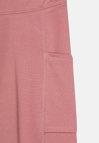 Leggings de sport roses avec une poche latérale, texture lisse et coutures renforcées, conçus pour le confort et la fonctionnalité.