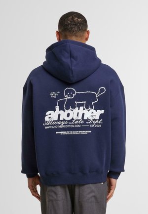 Navy blue hoodie with a graphic of a dog and text on the back. Made of cotton, featuring a soft texture and a drawstring hood.