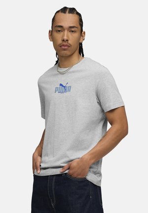 Grijze katoenen T-shirt met korte mouwen, voorzien van een blauw Puma-logo op de voorkant. De stof heeft een gladde textuur en een ontspannen pasvorm.