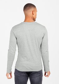 Langärmeliges graues T-Shirt aus Baumwollmischung, mit rundem Ausschnitt, figurbetontem Schnitt, glatter Textur, leicht meliertem Muster, Rückansicht mit leicht abgerundetem Saum.