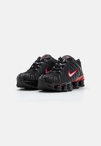 Schwarze Nike-Sneaker mit roten Akzenten, ausgestattet mit einem strukturierten Obermaterial, sicheren Schnürsenkeln und charakteristischen spiralförmigen Sohlen für verbesserten Komfort.
