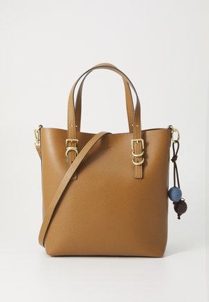 Brown leather tote bag with dual handles, adjustable shoulder strap, and gold hardware; features decorative two-pom detail on side.