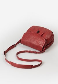 Borsa a tracolla rossa in pelle con una texture liscia, chiusura con zip e tracolla regolabile. Presenta un design sobrio con una patta curva.