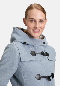 Blauwe wol dufflecoat met een capuchon, grote klepzakken, zwarte toggle-sluitingen en een geblokte voering. Gladde textuur, op maat gesneden pasvorm.