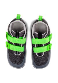 Zapatillas deportivas en gris y negro con dos correas de Velcro de color verde brillante, textura de malla, interior acolchado y suela de goma en contraste.