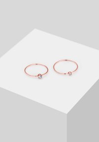 Orecchini a cerchio in oro rosa con una finitura lucida e un singolo cristallo trasparente su ciascun orecchino, caratterizzati da un design elegante e minimalista.
