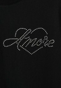 Crni dukserica s dizajnom od kristalića s riječi "love" u elegantnom rukopisu, oivičenom unutar oblika srca.