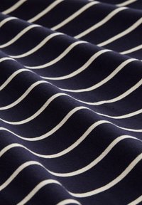 Marinblått tyg med texturerad yta som har flödande vita ränder, vilket skapar ett vågmönster över ytan. Mjuk, elastisk material.