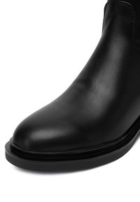 Hladká čierna kožená topánka s zaoblenou špičkou a hrubou čiernou podrážkou, zobrazená s detailným zobrazením z prednej a bočnej strany.