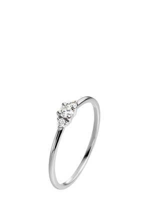 Anillo delgado de plata con tres pequeñas piedras redondas y transparentes colocadas juntas en la parte superior.