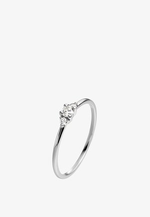 Anillo delgado de plata con tres pequeñas piedras redondas y transparentes colocadas juntas en la parte superior.