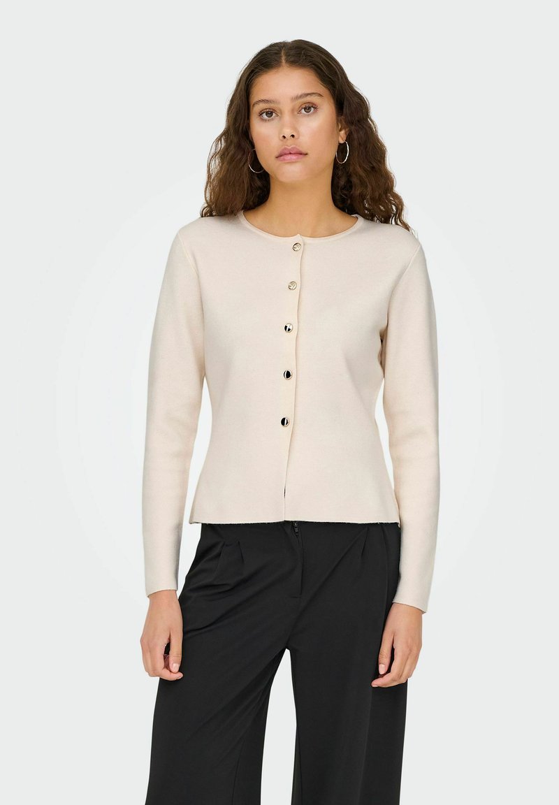 Cardigan beige clair à manches longues, col rond et six boutons dorés sur le devant. Tissu doux et coupe décontractée.