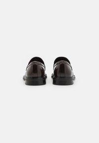 Zapatos de cuero marrón con un acabado liso, punta redondeada y suela de goma negra; con sutiles acentos de costura.