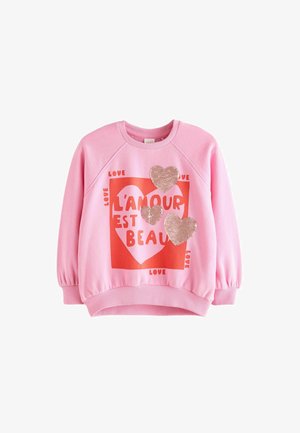 Rosa Sweatshirt mit einem roten Herz-Graphic und dem Text "L'amour est beau" sowie drei Paillettenherzen. Weicher Stoff, gerippte Bündchen.