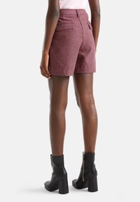 Punaiset ja valkoiset ruudulliset shortsit, jotka on valmistettu teksturoidusta kankaasta, kahdella takataskulla ja korkealla vyötäröllä, yhdistettynä mustiin nilkkabootseihin.