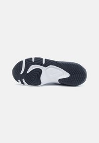 Svart og hvit såle på sneakers med bølgete tekstur, en fremtredende Nike-logo, og en konturert design for grep.