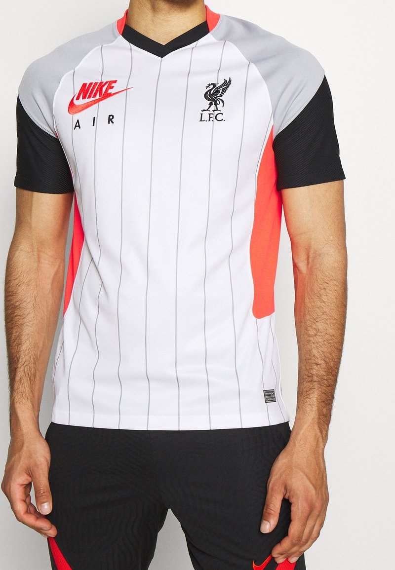 Homme portant un maillot de football Nike Air du Liverpool FC blanc avec des manches noires et de fines rayures verticales, assorti à un short noir.