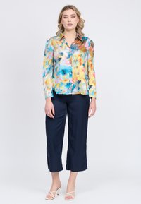 Camicia a maniche lunghe con colletto in un motivo floreale multicolore, con blu, gialli e rosa, abbinata a pantaloni cropped blu navy.