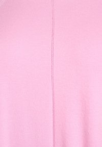 Jasnoróżta dzianina o gładkiej fakturze, z pionowym szwem biegnącym przez środek.