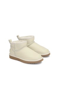 Baltas ādas potīšu zābaki ar teksturētu apdari, mīkstu iekšējo oderi un gumijas zoli. Iezīmējas ar salocītu apakšmalu un dekoratīvo šuvju. 