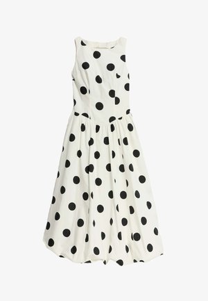 Witte mouwloze jurk met grote zwarte stippen, aansluitende lijfje en een zwierige rok met gathered details in de taille.