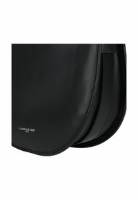 Borsa a tracolla nera in pelle con forma arrotondata. Presenta una texture liscia, cuciture visibili e dettagli del logo sulla parte anteriore.