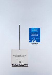 Zwei Kleidungsetiketten, die an einer schwarzen Schnur hängen, eines weiß mit Informationen über recyceltes Material und eines blau mit Details zur Wärmedämmung.