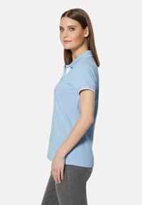 Lichtblauwe polo met een klassieke kraag, korte mouwen en witte accenten, gemaakt van glad katoen, fitted ontwerp.