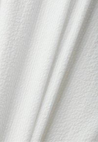 Tissu blanc avec un motif gaufré texturé subtil et de doux plis créant des ombres délicates et de la profondeur.