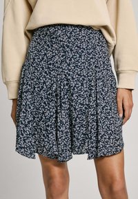 Gonna plissettata floreale blu navy realizzata in tessuto leggero, caratterizzata da piccoli motivi floreali bianchi e una vita aderente.