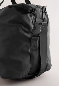 Must veekindel kott, millel on sile tekstuur, tugev rihm ja silmapaistev pannallukk. Minimalistlik disain, kompaktne kuju.