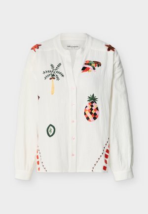 Valge pikkade varrukatega nööbitav särk, kaunistatud värvikate tikanditega troopiliste motiividega, sealhulgas ananass, palmipuud ja abstraktsed kujundid.