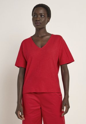 Red V-neck t-shirt with short sleeves, made of soft fabric; relaxed fit with a slightly textured surface. Paired with matching red trousers.