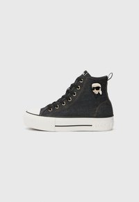 Sneaker alte in denim scuro con occhielli dorati. Presentano una punta bianca, una suola bianca a contrasto e un piccolo dettaglio di personaggio sul lato.