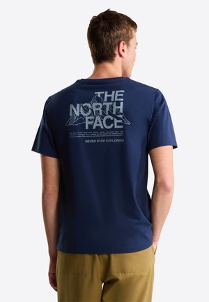 T-shirt bleu marine avec un grand motif blanc "THE NORTH FACE" au dos, illustré avec des montagnes et du texte. Manches courtes et col rond.