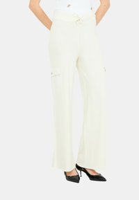 Pantaloni bianchi a gamba larga con vita regolabile, dotati di tasche laterali e dettagli in metallo color oro. Tessuto morbido e testurizzato per il massimo comfort.