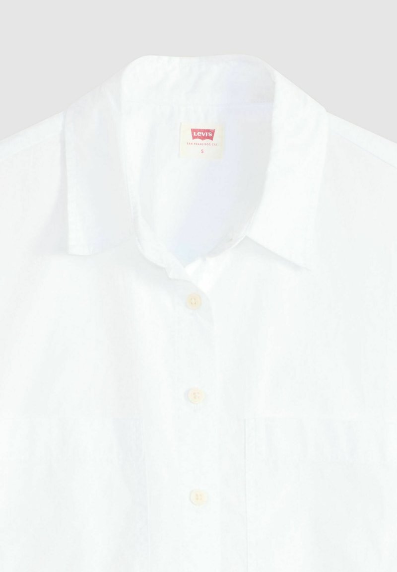 Camicia bianca con colletto classico. Realizzata in tessuto leggero, presenta un design semplice e bottoni beige. Include un'etichetta Levi's.