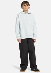 Felpa azzurra chiara con tasca frontale e logo "element" stampato, abbinata a pantaloni larghi neri e sneakers nere con suole in gomma.