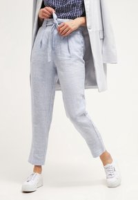 Ljusblå linnebyxor med avslappnad passform, som har knytband i midjan, veck och sidofickor, kombinerat med vita sneakers.