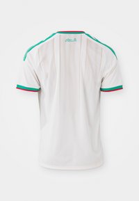 Witte sporttrui met groene en rode details op de mouwen en kraag, met een subtiel sterrenpatroon en Arabische tekst nabij de halslijn.