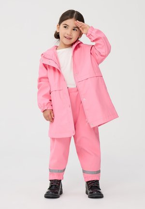 Giacca impermeabile rosa con cappuccio, chiusura a scatto e zip, polsini elasticizzati. Abbinata a pantaloni rosa coordinati con dettagli riflettenti.