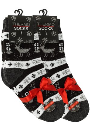 Calze termiche in bianco e nero con un motivo di renne, decorate con un nastro rosso sul risvolto. Il materiale appare morbido e caldo.