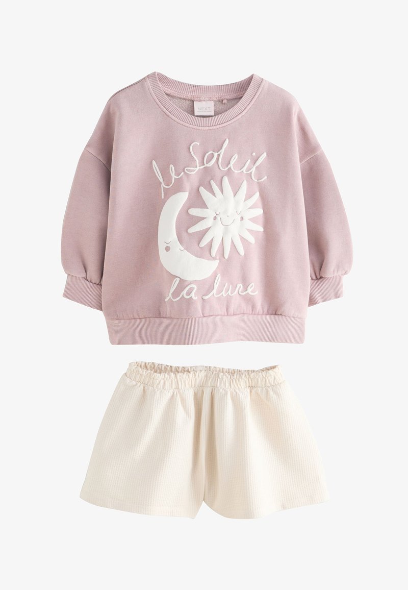Tenue enfant avec un sweat-shirt rose avec un motif de soleil et lune souriants et un short ivoire à taille élastique.