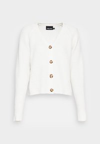 Cardigan de punto blanco con canalé, de manga larga, escote en V y cinco botones marrones en la parte delantera. Presenta un ajuste relajado y corto.
