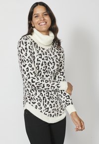 Leopardmönstrad polotröja i vitt och svart, med ribbade ärmslut och fåll, en rundad nederkant och mjuk textur.