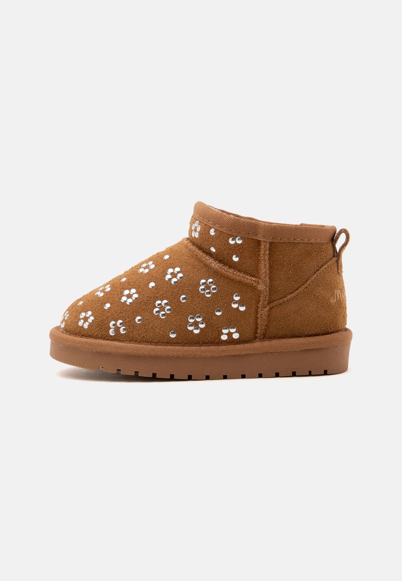 Καφέ σουέντ μποτάκι αστραγάλου με ασημί καρφωτά λουλουδένια σχέδια, επίπεδη καουτσούκ σόλα και ταινία έλξης στη φτέρνα σε λευκό φόντο.