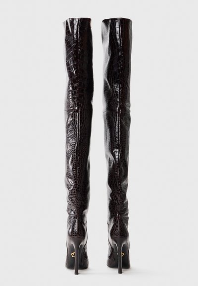 Lårhøje støvler lavet af mørkebrun krokodilleskindslook læder med en blank finish, der har stilletto hæle og minimal synlig hardware.